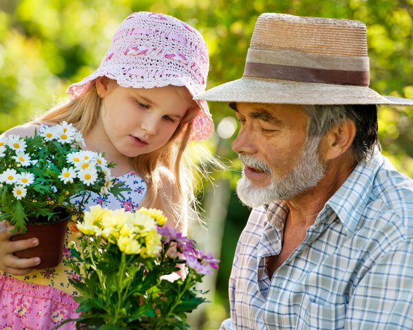 Ein Kind und ein älterer Herr unterhalten sich und haben jeweils Blumen in der Hand | © Alexander Raths - Fotolia