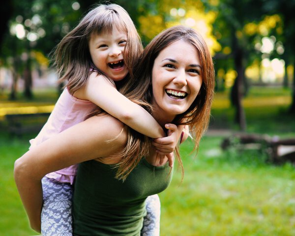 Eine Frau trägt eine Kind auf dem Rücken und beide lachen dabei | © shutterstock | nd3000